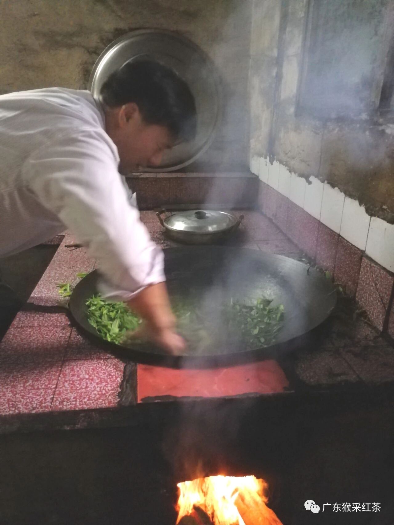 Wang Ronghe hand-pan-firing tea leaves in an iron wok over a wood fire